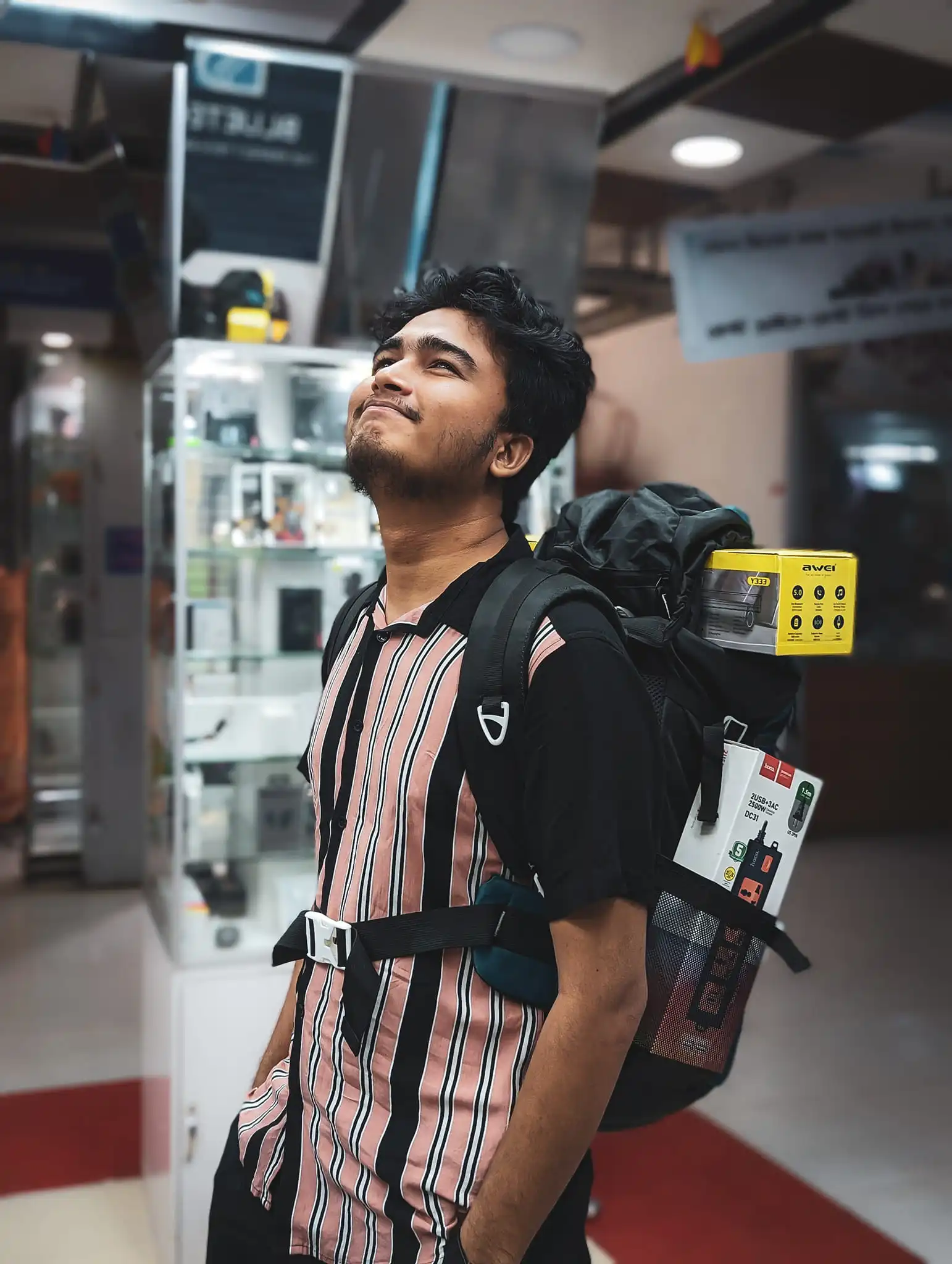 Looking up in a tech store with loaded backpack